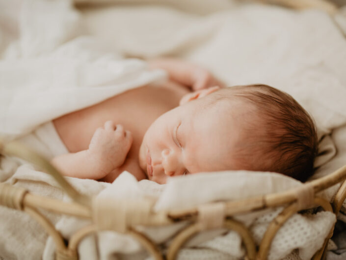 Ein Baby liegt während einem Newbornshooting auf dem Rücken, die Augen geschlossen.