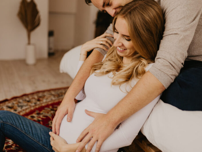 Ein Mann streichelt den Babybauch seiner Frau. Die Frau lächelt